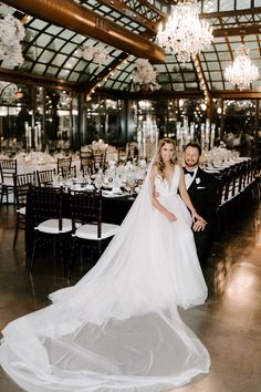 a bride and groom pose for a photo in front of their wedding reception tables at the grand america hotel