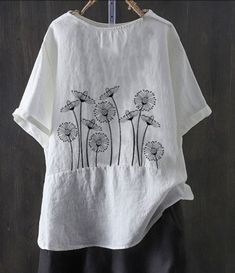 a white t - shirt with black dandelions on it