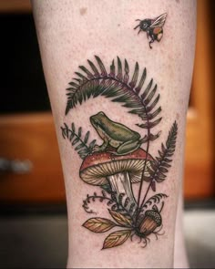 a green frog sitting on top of a mushroom with leaves around it and a bee flying by