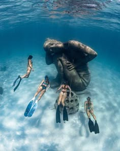 people are swimming in the water next to an elephant statue