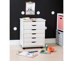 a white dresser sitting next to a wall with polka dot decals on the walls