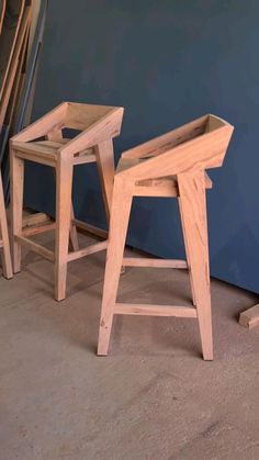 two wooden stools sitting next to each other in front of a blue painted wall