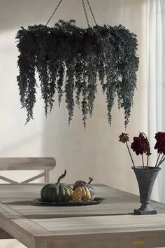 a dining room table with flowers and greenery hanging from it's centerpiece