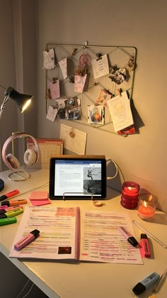 a tablet computer sitting on top of a desk next to a pile of papers and pens