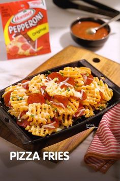 a tray filled with pasta and sauce next to a bag of pepperoni