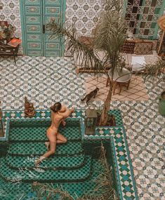 a naked woman sitting on top of a bath tub in a room filled with plants