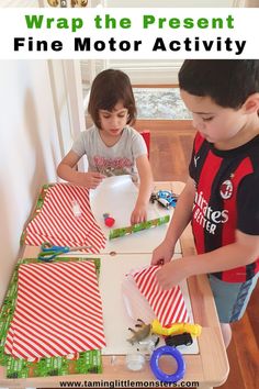 two young boys are making kites out of paper on a table with scissors and tape