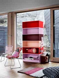 a room with a chair, bookshelf and sliding glass doors