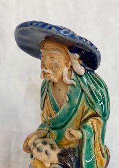 a ceramic figurine with a hat on it's head and a dog in his lap