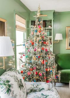 a living room with a christmas tree in the center and green walls, white couches