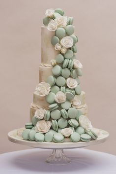 a three tiered cake decorated with flowers and macaroni shells on a table