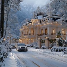 a car driving down a snow covered road in front of a large white building with lights on it