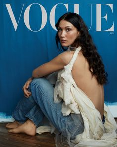 a woman is sitting on the floor in front of a blue wall and wearing jeans