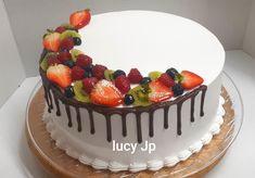 a white cake topped with fruit and chocolate drizzle