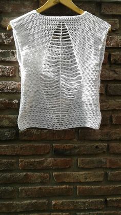 a white crocheted top hanging on a brick wall