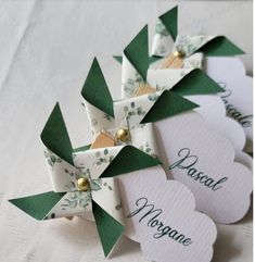 four small green and white pinwheels with name tags on them, sitting next to each other