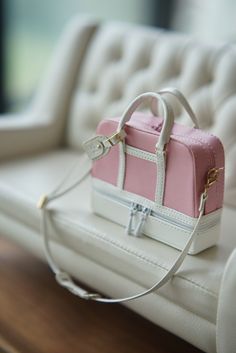 a small pink and white purse sitting on top of a table next to a couch