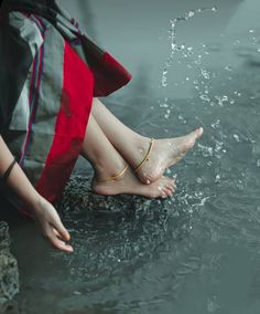 a woman is sitting in the water with her feet up