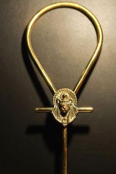 a golden cross with a lion head on it's side and a gold handle