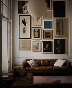 a living room filled with furniture and lots of pictures on the wall above it's couch