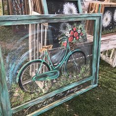 an old bicycle painted with flowers is in a frame on the grass near other frames