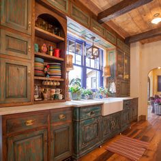 a kitchen with wooden floors and cabinets in the center, along with a large window