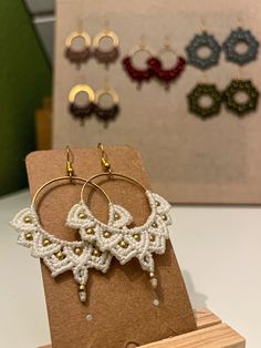 two pairs of earrings are on display in front of some other pieces of wood and paper