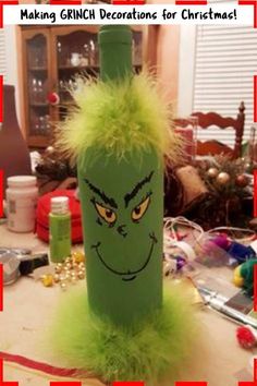 a green bottle with a grin face drawn on it, surrounded by other christmas decorations