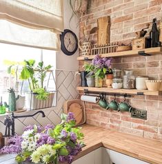 a brick wall with shelves filled with pots and pans next to flowers on the counter