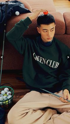 a young man sitting on the floor with golf balls in his hair