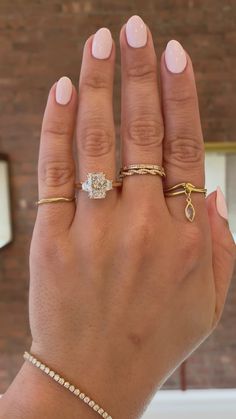 a woman's hand with three different rings on her left and one ring on the right