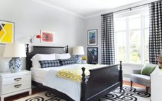 a bed room with a neatly made bed next to two chairs and a table in front of a window