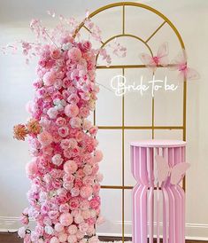 a pink and white flower covered table next to a tall vase with flowers on it