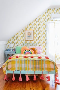 a bedroom with yellow and pink decor on the walls, wood flooring and a colorful bed