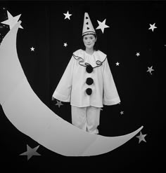 a black and white photo of a boy dressed up as a clown on the moon