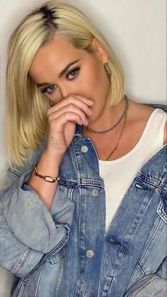 a woman with blonde hair and piercings wearing a denim jacket is posing for the camera