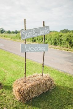 two wooden signs sitting on top of a hay bale in the middle of a field