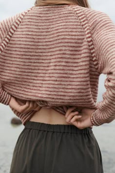 the back of a woman's sweater that is open and has her hands on her hips