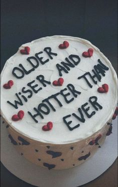 a white cake with red hearts on it that says older and wiser than ever