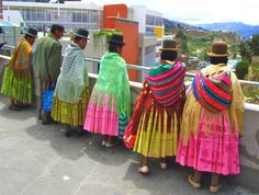 several people in colorful dresses standing on a balcony looking out at the city and mountains