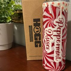 a red and white drink sitting on top of a wooden table next to a box