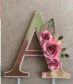 the letter a is decorated with pink flowers and leaves on top of two metal hooks