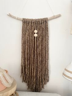 there is a wall hanging made out of yarn and wooden beads with two buttons on it