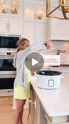 a woman standing in a kitchen next to an open pot on top of a counter