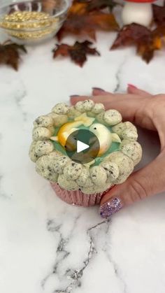 a woman is holding a small bird's nest made out of rocks and marbles