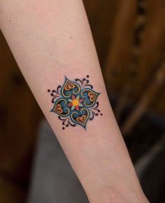 a small tattoo on the wrist of a woman's arm with an ornamental design