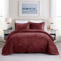 a bed with a red comforter and pillows