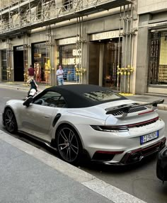 a silver sports car parked on the side of the road in front of a building