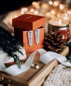 a box with two pairs of earrings sitting on top of it next to some christmas decorations