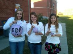 three girls are holding up some balls on the sidewalk